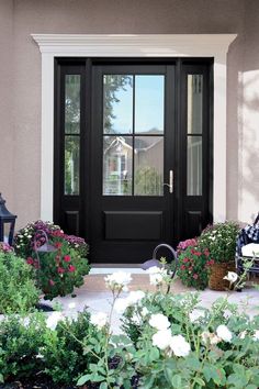 a black front door with white flowers and pumpkins