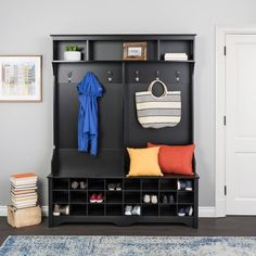 a black coat rack with shoes and purses on it next to a blue rug