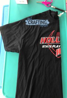 a black t - shirt with the word holli state play on it next to some scissors