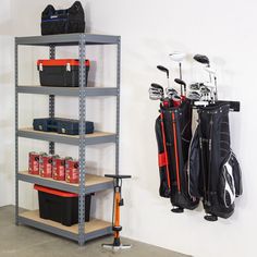 a rack filled with golf clubs next to a wall mounted bag holder and storage bin