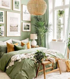 a bedroom with green bedding and pictures on the wall above it, along with potted plants