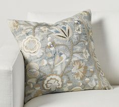 a white couch with a blue and gold pillow on it's back end,