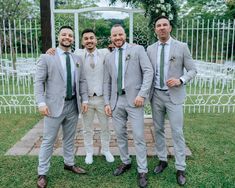 three men in suits and ties standing next to each other near a white gazebo