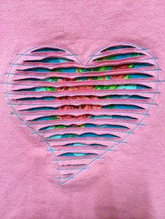 a pink t - shirt with blue and green strips in the shape of a heart