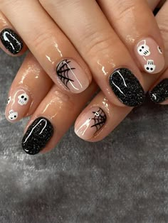 a woman's nails with black and white designs on them, including spider webs