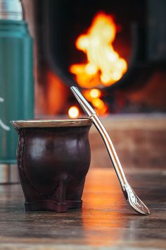 a cup with a spoon in it sitting next to a fire place