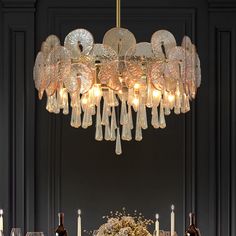 a chandelier hanging over a dining room table with wine glasses and plates on it