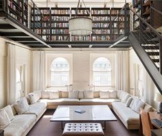 a living room filled with lots of furniture and bookshelves next to a stair case