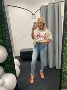 a woman standing in front of a mirror taking a selfie with her cell phone