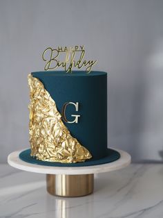 there is a blue and gold cake on top of a white plate with the word happy birthday written on it