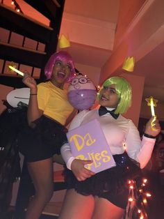 two women dressed up in costumes posing for the camera, one holding a box and the other holding a toy