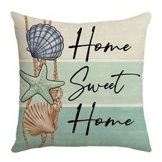 a pillow with the words home sweet home and seashells hanging from a rope