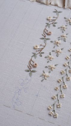 some white flowers and leaves are on a piece of fabric that has been stitched together