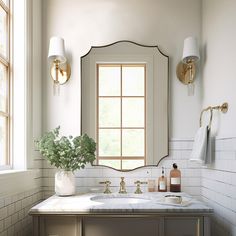 a bathroom with a sink, mirror and vase on the counter in front of it