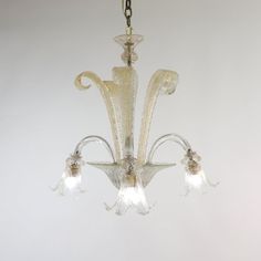 a glass chandelier hanging from a chain with three lights on each end and one light in the middle