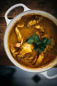 a pot filled with food and garnished with cilantro on the side