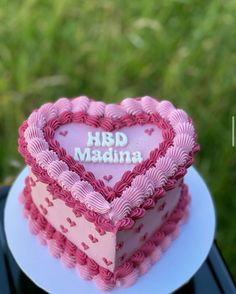 a heart shaped cake with the words hbd madna on it sitting on a plate