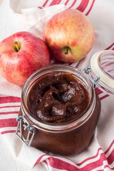 two apples sitting next to a jar of chocolate pudding