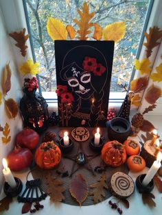 a table topped with candles and pumpkins next to a window