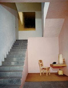 there is a table and two chairs on the floor in this room with stairs leading up to the ceiling