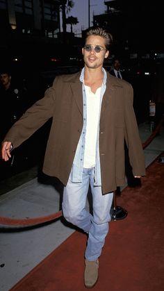 a man walking down a red carpet with his hand in his pocket and sunglasses on