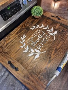 a wooden cutting board sitting on top of a counter next to an oven and microwave