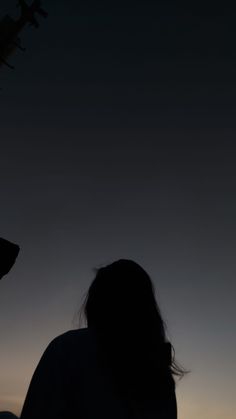 the silhouette of a person looking at an airplane in the sky