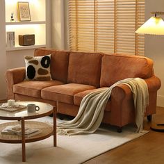 a living room with a brown couch and coffee table in front of the window covered by a blanket