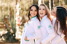 three beautiful young women standing next to each other in front of some trees and lights