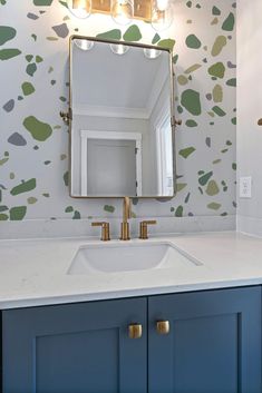 a bathroom sink with a mirror above it and wallpaper on the walls behind it