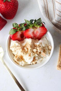 two strawberries sit on top of a bowl of ice cream next to crackers