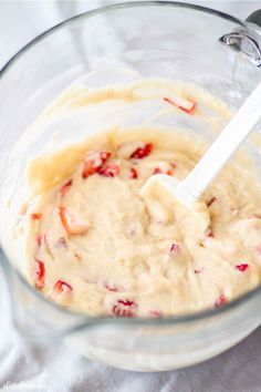 a glass bowl filled with batter and strawberries