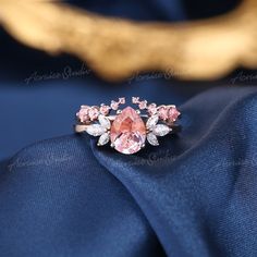 a pink diamond ring sitting on top of a blue cloth