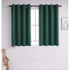 a window with green curtains hanging on the side of it and a chair next to it