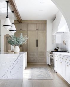 a large kitchen with white cabinets and marble counter tops, along with an archway leading to the dining room