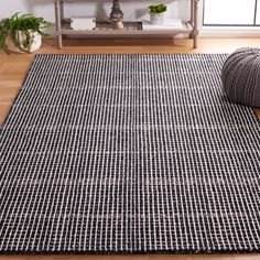 a black and white area rug on the floor in front of a shelf with potted plants