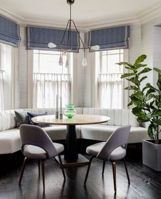 a living room filled with furniture and a round table surrounded by chairs next to a potted plant