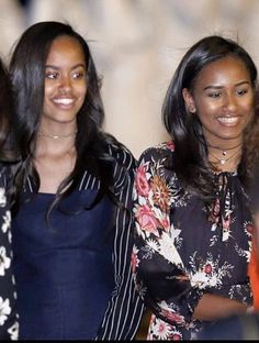 two women standing next to each other smiling for the camera with another woman in the background