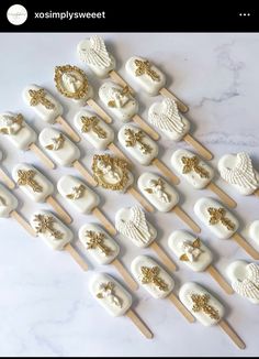 white and gold cupcakes on wooden sticks are arranged in the shape of angel wings