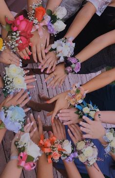 a group of people with their hands in the shape of a circle holding flowers and ribbons