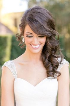 a woman in a wedding dress smiling at the camera with her long hair pulled back