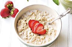 a bowl of oatmeal with strawberries on the side