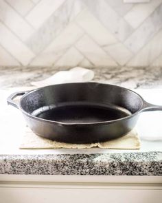 a cast iron skillet sitting on top of a kitchen counter next to a towel