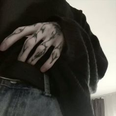 a person with tattoos on their hands and hand holding something in his other hand while wearing a black shirt