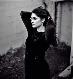 a black and white photo of a woman leaning against a wall with her hand on her head