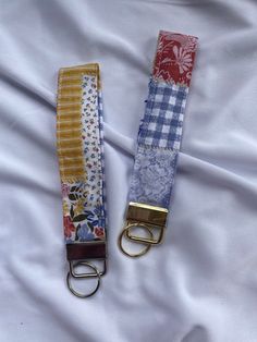 two key fobs are laying on a white sheet with blue and red flowers