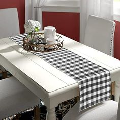 a white table topped with a black and white checkered table runner next to a window