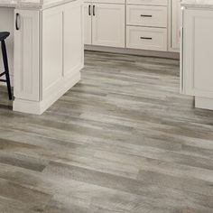 a kitchen with white cabinets and wood flooring is shown in this image, there are two stools on the counter