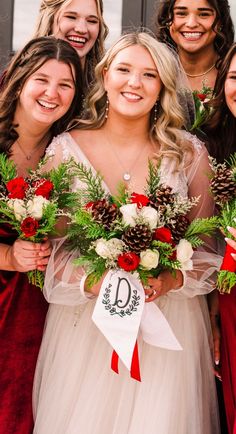 a group of women standing next to each other holding bouquets and pine cones in their hands