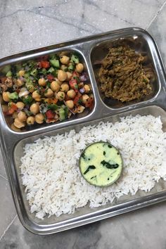 a metal tray filled with rice, vegetables and other foods on top of each other